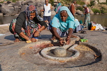 India, Karnataka, Hampi, Pilgrims make an offering at a lingam beside the Tungabhadra River in Hampi.