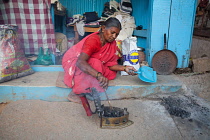 India, Karnataka, Hospet, Woman at a laundry stall filling an iron with hot coals.