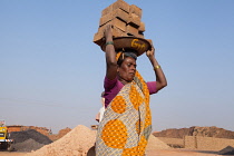 India, Karnataka, Harihar, Labourer carrying bricks on her heads at a brick factory in Harihar.