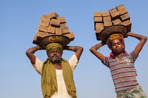 India, Karnataka, Harihar, Labourers carrying bricks on their heads at a brick factory in Harihar.