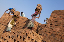 India, Karnataka, Harihar, Labourers carrying bricks at a brick factory in Harihar.