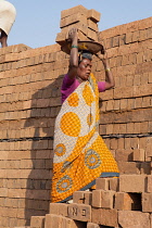 India, Karnataka, Harihar, Female labourer carrying bricks on her head at a brick factory in Harihar.
