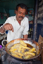 India, Karnataka, Hassan, Food hotel vendor frying chilli bhajis.