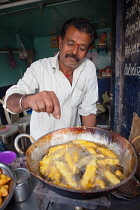 India, Karnataka, Hassan, Food hotel vendor frying chilli bhajis.