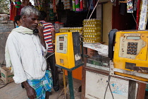 India, Karnataka, Hassan, Man using a public phone in Hassan.