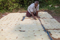 India, Kerala, Varkala, A man spreads out circular pieces of thin rolled dough to dry in the sun.