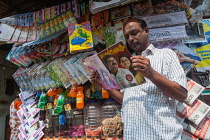 India, Kerala, Varkala, Man reading a magazine at a newspaper stall in Varkala.