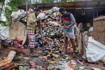 India, Kerala, Varkala, Men crushing cans at a recycling plant in Varkala.