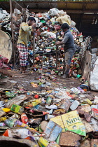 India, Kerala, Varkala, Men crushing cans at a recycling plant in Varkala.