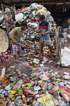 India, Kerala, Varkala, Men crushing cans at a recycling plant in Varkala.