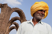 India, Karnataka, Bijapur, Portrait of a local man in front of the arches of the Bara Kaman .