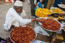 India, Karnataka, Bijapur, Sweet food and snack vendor in Bijapur market.