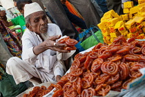 India, Karnataka, Bijapur, Sweet food and snack vendor in Bijapur market.