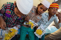 India, Maharashtra, Dhule, Muslim boys eating chana choor served from a street stall.