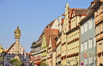 Germany, Bavaria, Rothenburg ob der Tauber, Colourful row of house patterns and fountain statue on Herrngasse off Marktplatz.