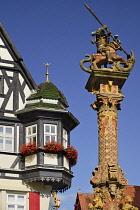 Germany, Bavaria, Rothenburg ob der Tauber, Marktplatz, St Georges Fountain with figure on horseback on a pedestal and oriel window plus statue of the Virgin Mary behind.