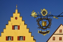 Germany, Bavaria, Rothenburg ob der Tauber, Detail of colourful building on Marktplatz with wrought iron sign in foreground.