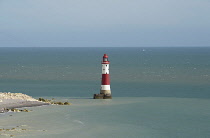 England, East Sussex, Beachy Head, Red and white painted lighthouse at base of cliffs.