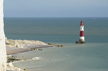 England, East Sussex, Beachy Head, Red and white painted lighthouse at base of cliffs.