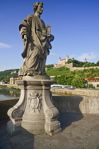 Germany, Bavaria, Wurzburg, Festung Marienberg above the River Main with a statue of St Totnan on Alte Mainbrucke.