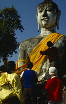 Thailand, Worshippers dressing Buddha statue.