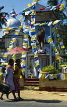 Sri Lanka, Kochchikade, St Josephs Church exterior decorated in flags with statue of Saint David and two passing girls.