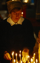 Russia, St Petersburg, Church warden attending to burning candles.
