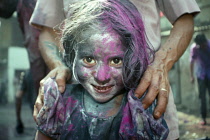 India, West Bengal, Calcutta, Young girl covered in coloured water and powder or gulal during Holi Festival celebrations.