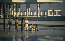 Pakistan, Islamabad, Faisal Mosque. Muslims at prayer in courtyard reflected in surface of marble floor.