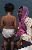 India, Delhi, Sikh mother washing young child in temple pool.