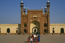 Pakistan, Punjab, Lahore, Badshahi mosque. Family standing in courtyard outside entrance of mosque attached to the Royal Fort built c. 1673 during reign of the Mughal emperor Aurangzeb.