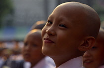 Thailand, North, Chiang Mai, Portrait of novice monk at mass ordination ceremony.