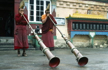 India, West Bengal, Ghum, Two Yellow Sect Buddhist monks at Choling monastery near Darjeeling playing long horns.