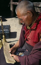 India, Ladakh, Religion, Elderly Buddhist monk reading old texts.