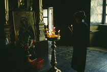 Russia, General, Church interior with woman lighting candles in front of icon.