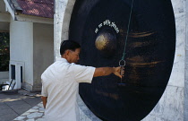 Thailand, Chiang Mai , Wat Doi Suthep, Man standing by a large Gong holding small hammer.