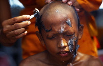 Thailand, Bangkok , Klong Toey , Wat Sapan. Novice ordination young boy having his head shaved by monk.
