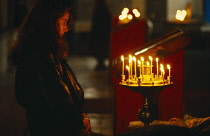 Russia, St.Petersburg, Young woman lighting candles during Catholic service.