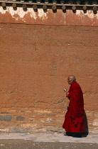 China, Gansu , Xiahe, Labrang Monastery, Monk with prayer beads and hand held prayer wheel.