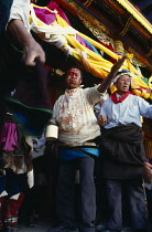 China, Qinghai Province, Religion, Blood letting ceremony during Tibetan festival. Man dancing after cutting his head with a knife watched by others.