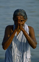 India, West Bengal, Sagar Island, Sagar festival woman pilgrim praying in the Ganges.