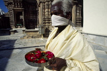 India, Gujarat, Palitana, Jain pilgrim with offering of flowers at Shatrunjaya or Place of Victory wearing white robe and scarf over mouth to avoid accidently swallowing an insect .