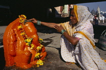 India, Maharashtra, Nasik, Woman making offering at Ganesh shrine.