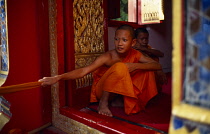 Thailand, Phrae Province , Buddhist novice monk pulls a cord attached to a gong.