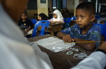 Thailand, Chiang Mai, Small boy studying the Koran at Chiang Mai Mosque.