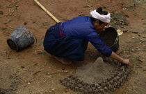 China, Yunnan Province, Menghun, Dai woman making raised religious symbol on ground.