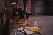 Pakistan, Punjab, Lahore, Badshahi Mosque,  Interior with Muslim pilgrim preparing meal.