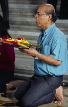 Thailand, South, Bangkok, Wat Meuang the City pillar the most important animist shrine in Bangkok with male devotee making an offering