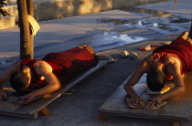 India, Bihar, Bodhgaya, Buddhist pilgrims prostrate on wooden boards.