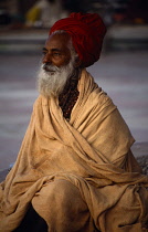 India, Uttar Pradesh, Rishikesh, Elderly Hindu male pilgrim with red turban and grey beard  wrapped in blanket.